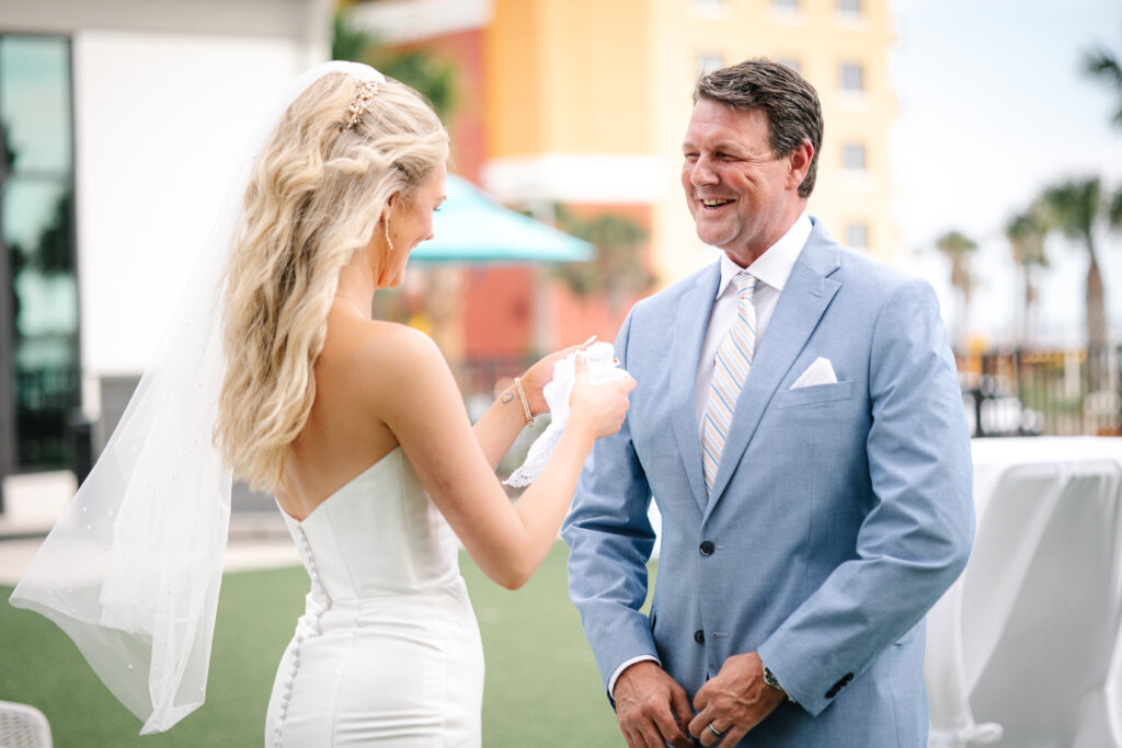 Bride sharing an emotional moment with her father before the ceremony, smiling as she reads from a hand-knitted handkerchief.