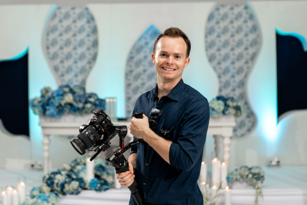 Matthew Oakes, founder and filmmaker at White Sands Weddings, holding a camera ready for wedding videography.