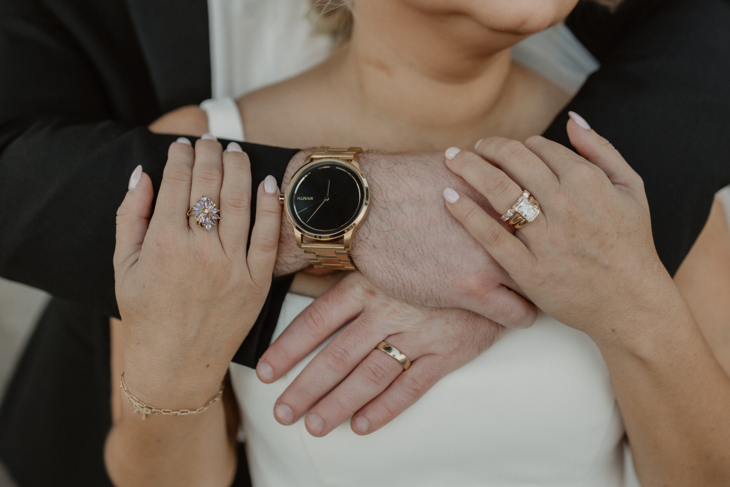 Intimate detail shot of the groom's hand resting on the bride's, showcasing wedding rings during a Gulf Coast wedding portrait session.