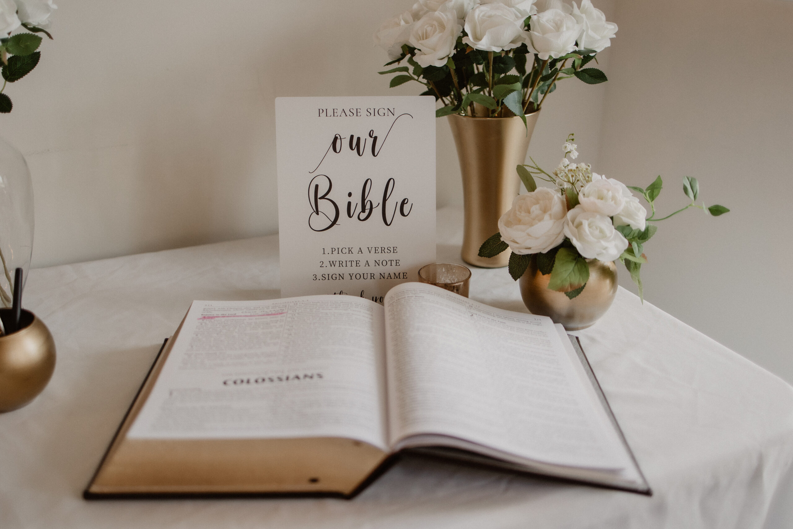 Open family Bible displayed with white florals and an "Our Bible" card, a faith-centered detail from a Gulf Coast Christian wedding ceremony.