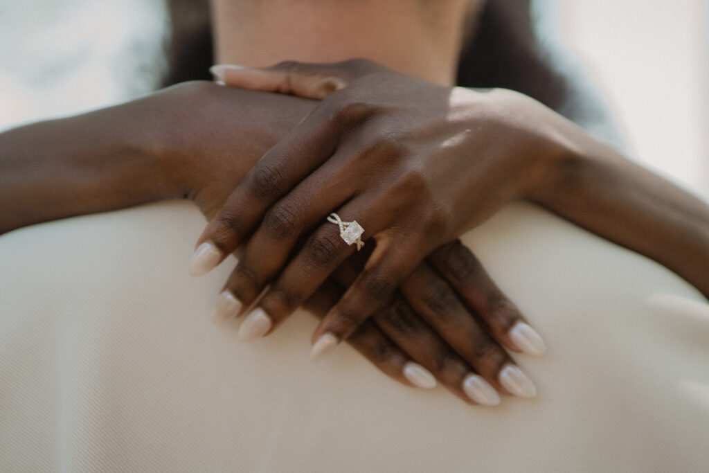 Close-up detail of newlyweds' hands showcasing their wedding bands during an intimate Gulf Coast wedding portrait.